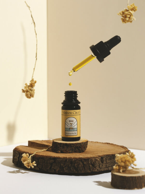 Huile de CBD à l'immortelle, mise en scène avec fleurs d'immortelle.